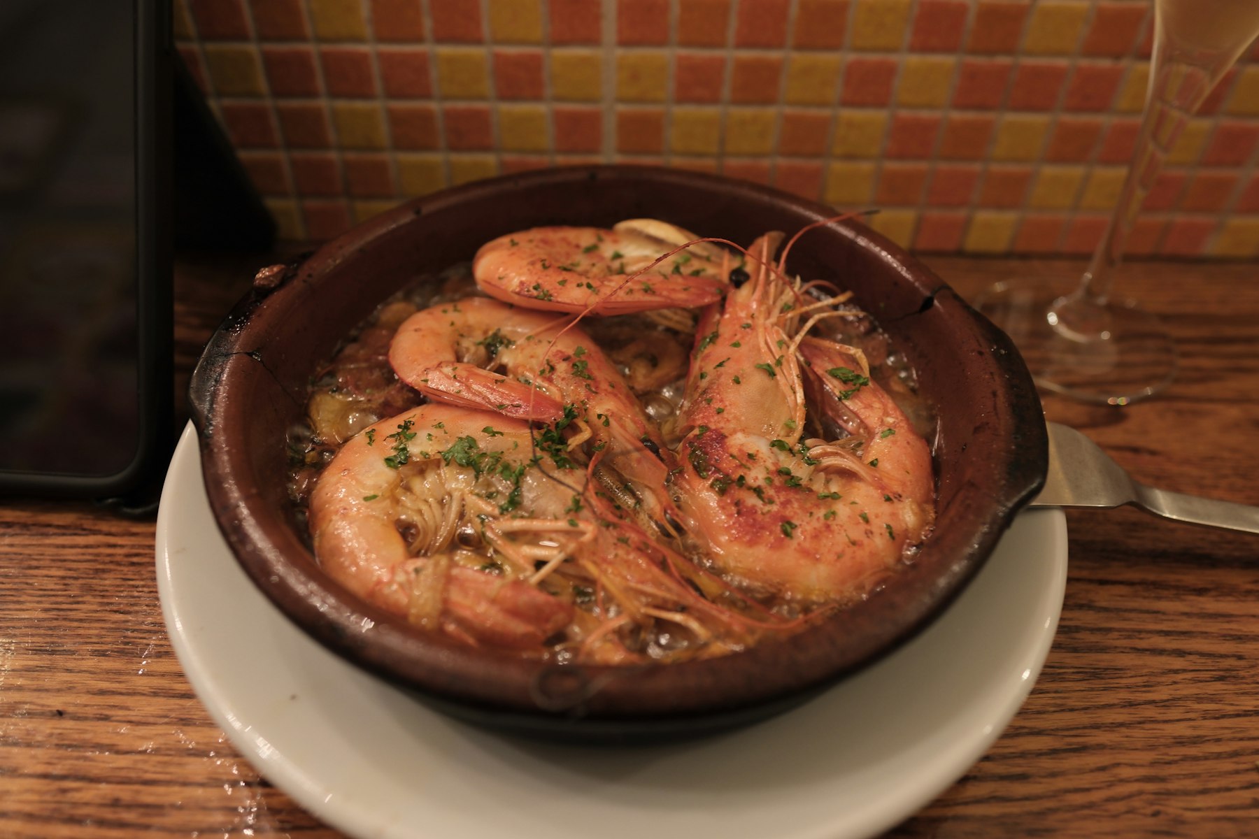Gambas al ajillo i leirfat: store reker i hvitløksolje, strødd med persille.